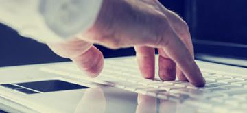 Hand tippt auf Laptop